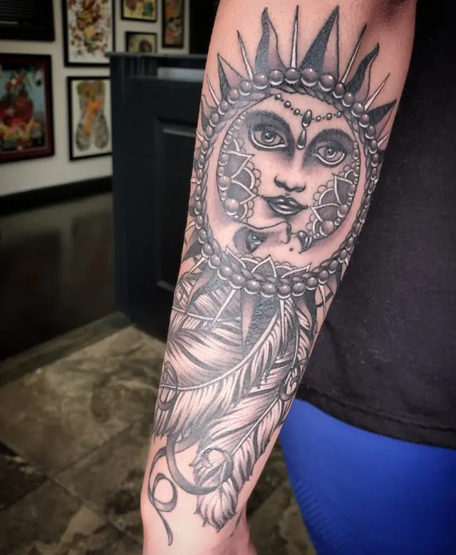 Ornamental black and gray sun face with feathers by Chris Carp at Heart & Sword Tattoo